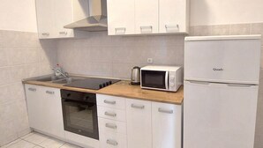 A compact kitchen with white cabinets, a built-in oven, a microwave, and a refrigerator. - A family apartment close to the beach - Dara 4 (Monterol)