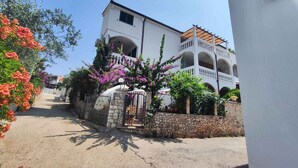 A two-story building with a stone wall and a gated entrance.