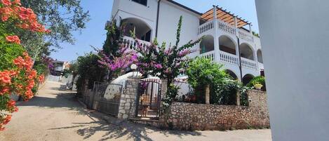 A two-story building with a stone wall and a gated entrance.