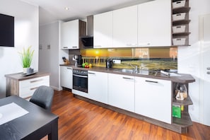 Une cuisine moderne avec des meubles blancs, un four encastré et un grand îlot central doté d’un évier.
