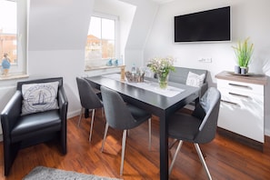 Un espace repas moderne avec une table en bois foncé, quatre chaises grises et un meuble blanc avec des tiroirs.