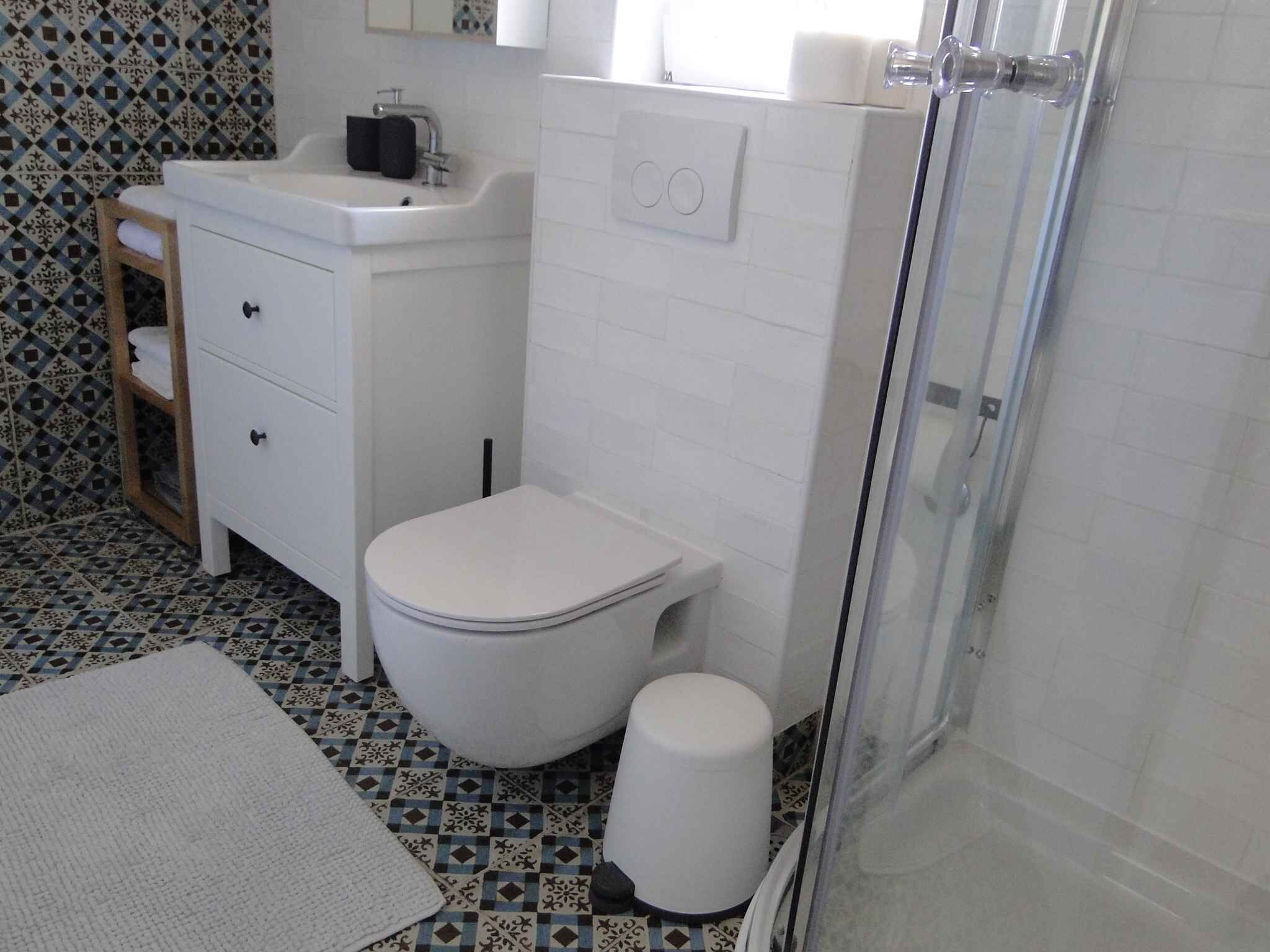 A bathroom with a white toilet, a sink, a mirror, and a shower.