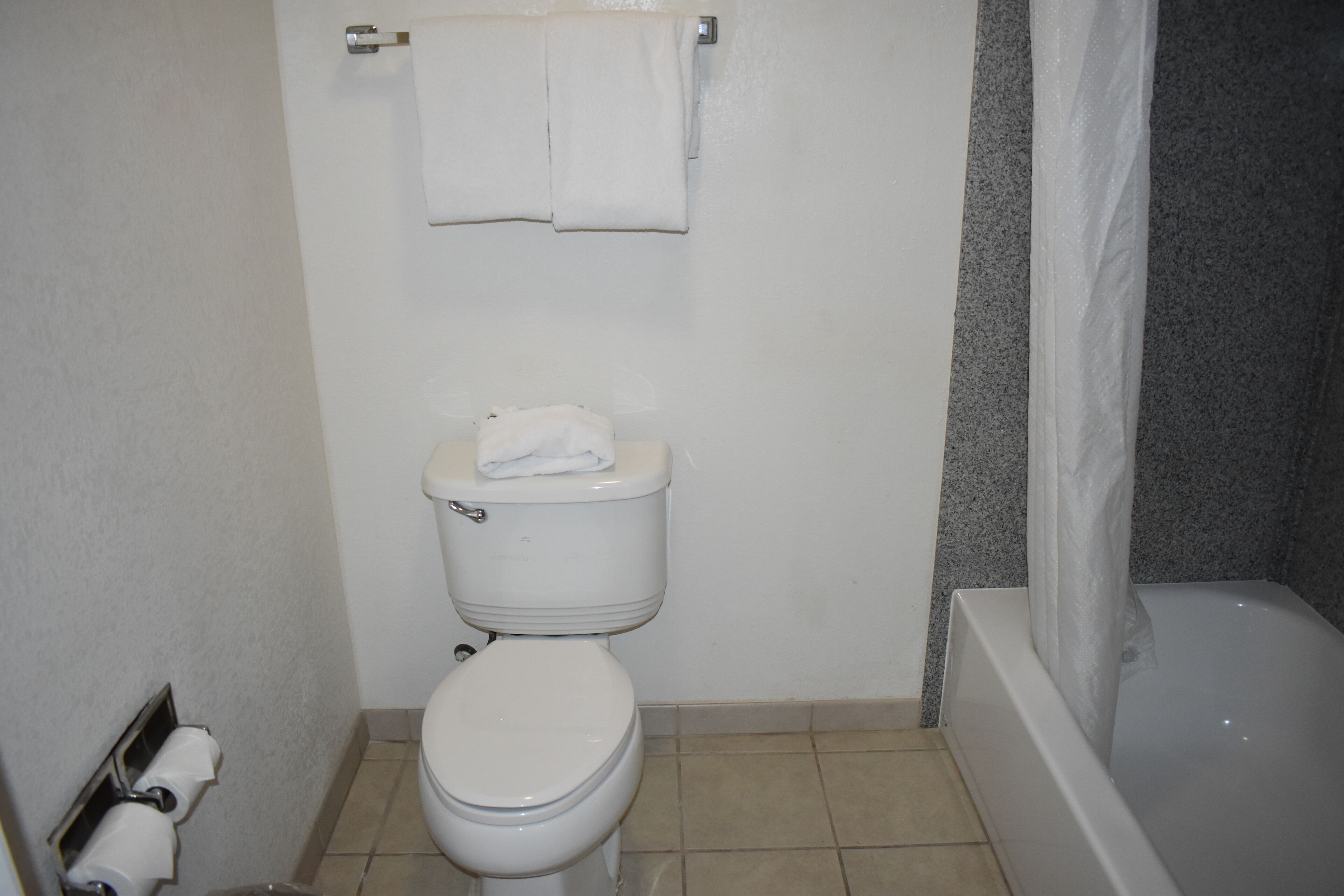 A bathroom with a toilet, a towel rack, and a bathtub.