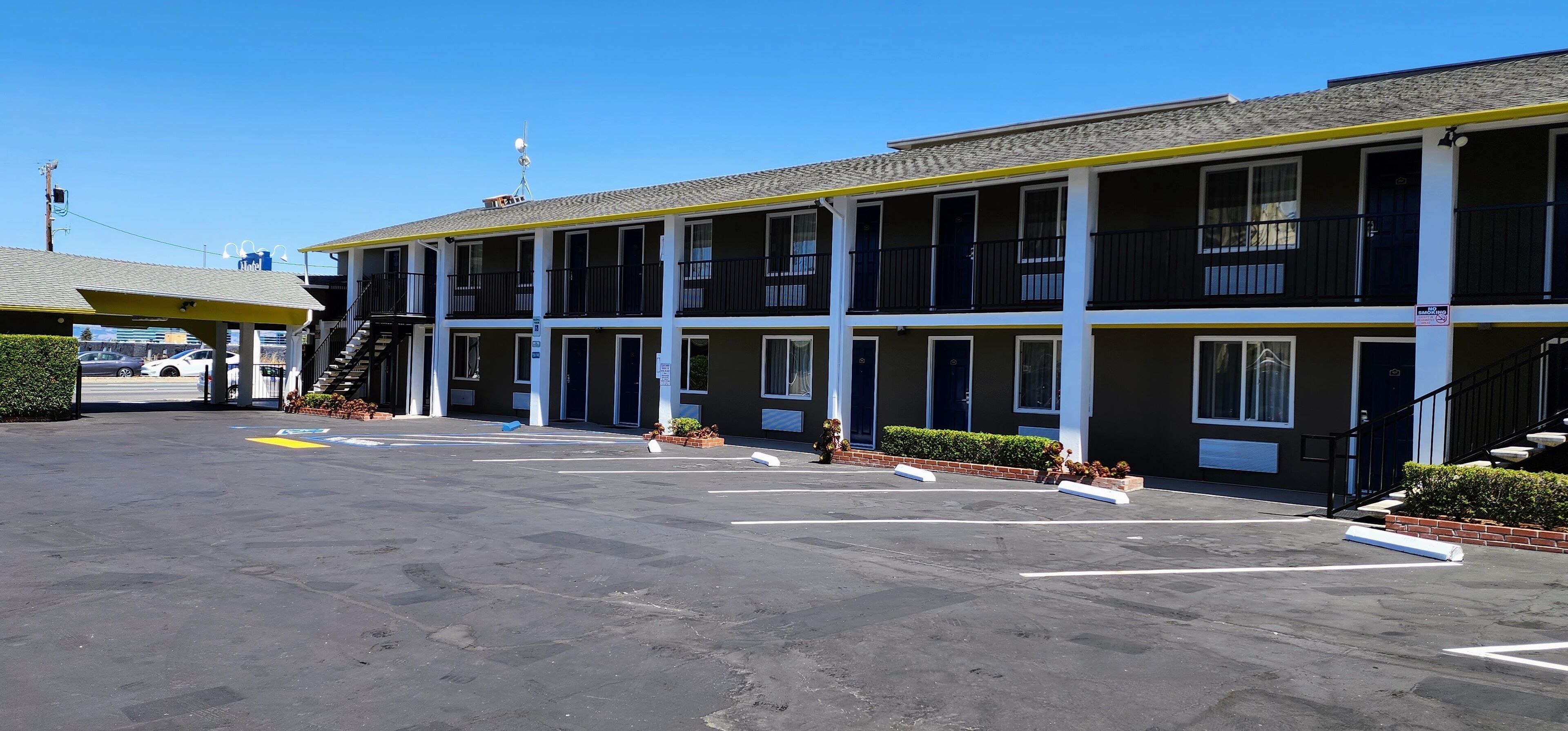 A motel with multiple floors, outdoor parking, and a clear sky.