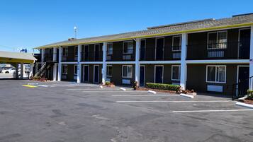 A motel with multiple floors, outdoor parking, and a clear sky.