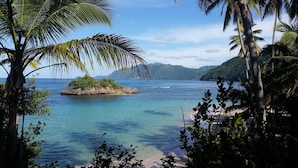 A tropical beach with clear blue waters, a small rocky island, and lush greenery. - Casa Picaflor (Las Terrenas)