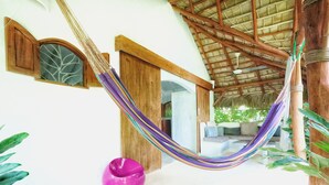 A hammock in a room with a thatched roof, wooden beams, and a white wall. - Casa Picaflor (Las Terrenas)