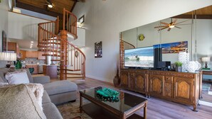 Un salón espacioso con una escalera de madera, un televisor de pantalla plana grande y un comedor con un aparador de madera.