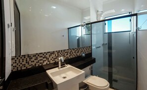 A modern bathroom with a black countertop, a white sink, and a glass-enclosed shower. - Recanto Rio Grande (São João Batista do Glória)