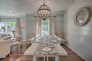 Enjoy meals in this elegantly set dining area with a long table, chandelier, and large clock.