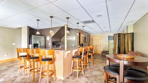 Un área de bar con taburetes de madera y mostrador de bar también de madera.