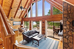 A spacious living area with a wooden ceiling, large windows, a stone wall, a leather sofa, and a dining table. - Lakefront Keowee Home w/ Dock, 14 Mi to Clemson (Seneca)