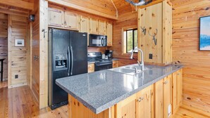 Cocina de cabaña de madera con refrigerador, microondas, estufa y lavabo.