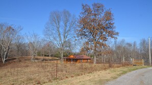 A rustic cabin with a wooden exterior, surrounded by a fenced property and leafless trees, indicating a rural setting. - Peaceful Farm Atmosphere (Gainesboro)