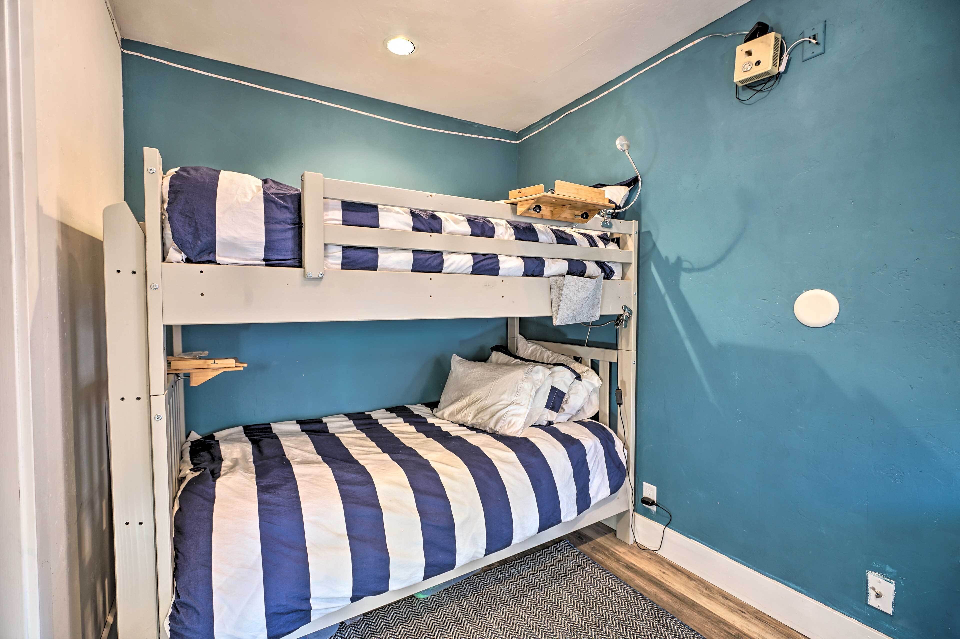 Camera con letto a castello, parete blu, una lampada a soffitto e una presa di corrente.