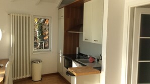 A compact kitchen with a window, a radiator, and a trash bin. - Superb villa with panoramic view over Lake Maggiore (Pollino)