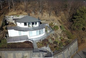 Une maison moderne de plain-pied, dotée d’un toit incurvé, de grandes fenêtres et de fondations en pierre.