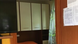 A room with a bed, a television, and a wooden wardrobe.