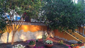 A landscaped garden with various plants and flowers, a stone wall, and a yellow staircase.