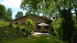 A stone building with a patio and outdoor seating area. - CANXAI THE RURAL TOURIST HOUSE OF LA GARROTXA PER ENJOY AMB QUI MÉS ESTIMES (La vall de Bianya)