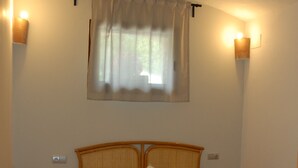 A bedroom with a bed, two bedside tables, a nightstand, a window with curtains, and wall-mounted lights. - CANXAI THE RURAL TOURIST HOUSE OF LA GARROTXA PER ENJOY AMB QUI MÉS ESTIMES (La vall de Bianya)