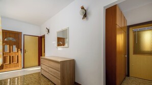 Un couloir avec des portes en bois, une commode en bois et un miroir fixé au mur.
