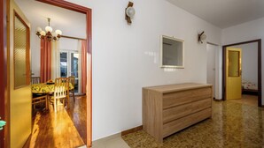 Une pièce comprenant une commode en bois, une table à manger avec des chaises et un miroir au mur.