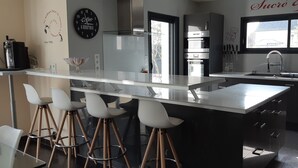 Una cocina moderna con una isla central, taburetes de bar, horno empotrado y un ventanal que proporciona luz natural.