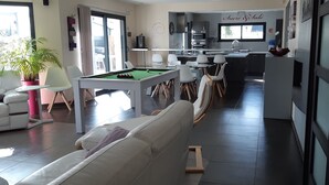Una sala de estar moderna con mesa de billar, un sofá y un comedor con sillas.