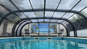 Piscina techada con vista a palmeras y al océano a través de amplios ventanales.