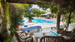 An outdoor pool area with lounge chairs and a covered seating area. - Apartment with Pool and Park in Villa Oasi (Santa Barbara)