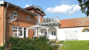 Ett tvåvåningshus i tegel med en balkong, en satellitantenn och en vit garageport.