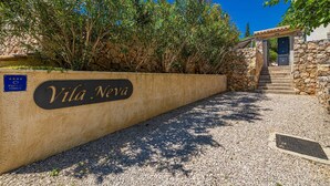 A stone wall with a sign reading "Villa Neva" and a small building with a stone staircase.