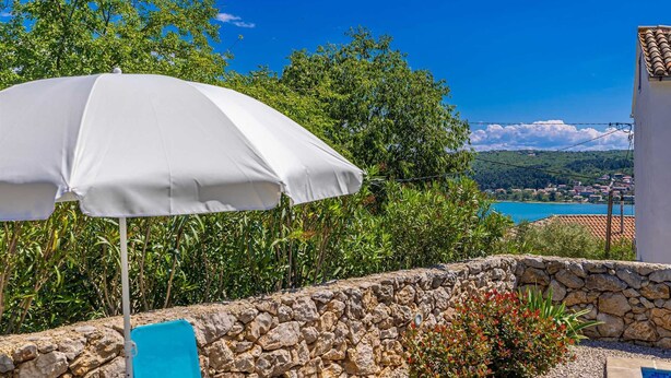 A white umbrella, a stone wall, and a view of a coastal town.
