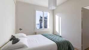 A bedroom with a bed, a window, a radiator, and a door. - Le Timonier - Two Bedroom Apartment, Sleeps 4 (Saint-Malo)