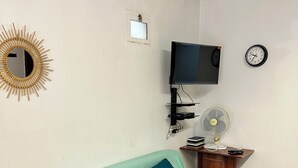 A living room with a sofa, a coffee table, a television, a clock, and a wall-mounted fan. - Family villa with private pool in Lloret de Mar - 3 bedrooms - quiet (Lloret de Mar)