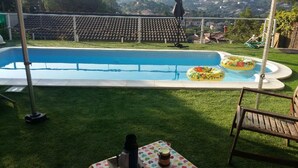 A swimming pool with inflatable rings, a table with a jar, and a chair. - Family villa with private pool in Lloret de Mar - 3 bedrooms - quiet (Lloret de Mar)