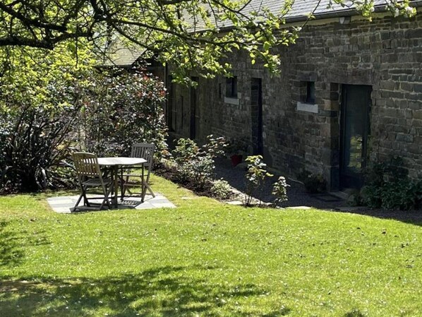 A stone building with a small patio and a table with chairs.