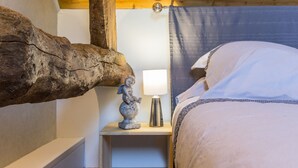 Een slaapkamer met een bed, een nachtkastje met een lamp en een decoratieve sculptuur.