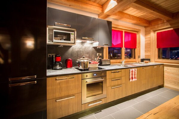 A modern kitchen with wooden cabinets, a built-in oven, a microwave, and a coffee maker. - Wonderful chalet, 50 m from the slopes (Les Deux-Alpes)