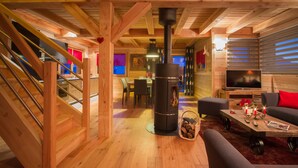 A cozy wooden interior with a fireplace, a dining area, and a living room with a sofa and a TV. - Wonderful chalet, 50 m from the slopes (Les Deux-Alpes)
