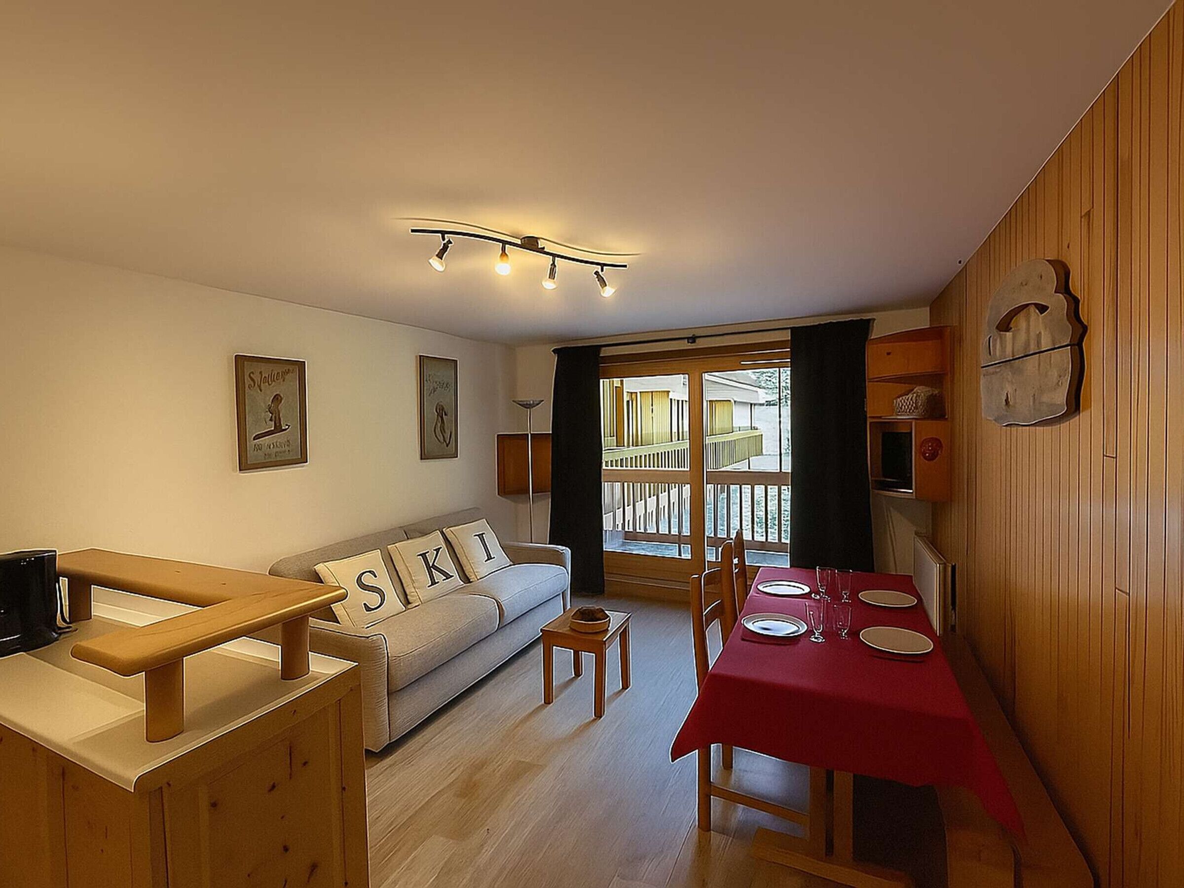 A cozy living room with a sofa, a dining table set for four, and a wooden bench.