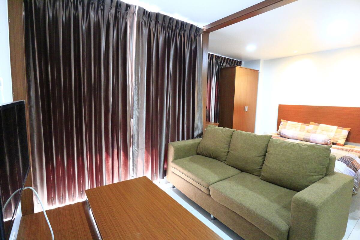 A living room with a sofa, a wooden table, and a television.