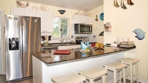 A modern kitchen with stainless steel appliances, white cabinetry, and a central island with bar stools. - Best Location for Your best vacation!  (Islamorada, Village of Islands)