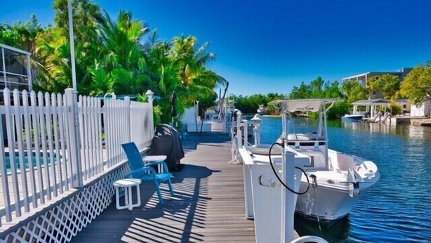 A wooden dock with a white fence, a boat, and a row of chairs and tables. - Best Location for Your best vacation!  (Islamorada, Village of Islands)
