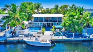 A waterfront property with a dock, a boat, and a pool area surrounded by palm trees. - Best Location for Your best vacation!  (Islamorada, Village of Islands)