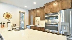 Una cocina moderna con armarios de madera, electrodomésticos de acero inoxidable y encimera de mármol.