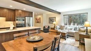 Una cocina moderna con armarios de madera, electrodomésticos de acero inoxidable y un comedor con una mesa redonda y sillas.