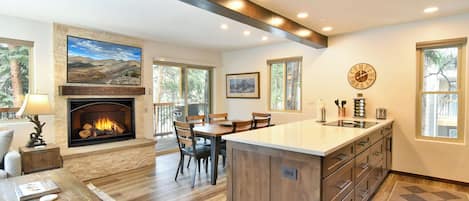 A spacious kitchen with a central island, a fireplace, and a dining area.
