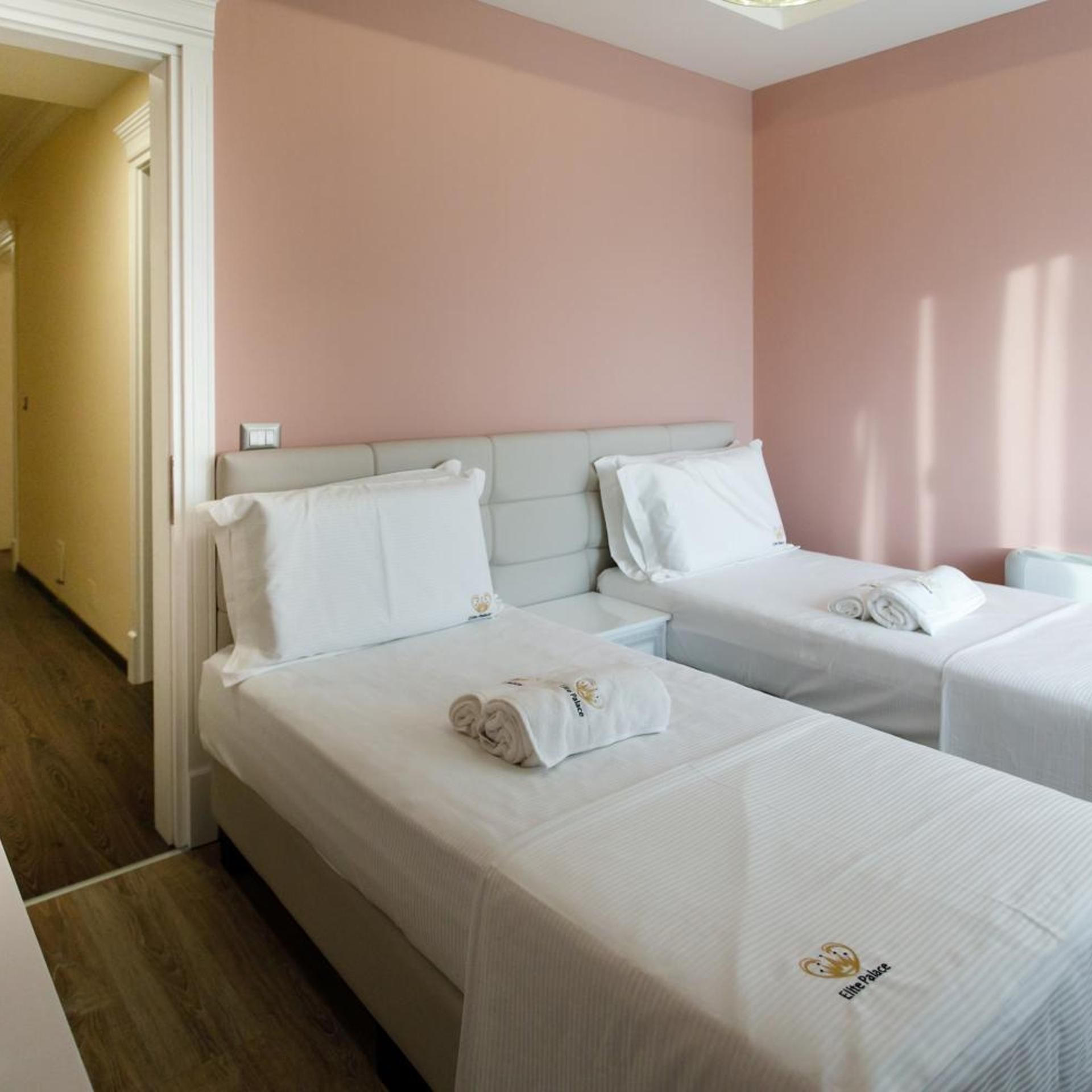 Una habitación de hotel con dos camas, cada una con una almohada y una toalla enrollada.